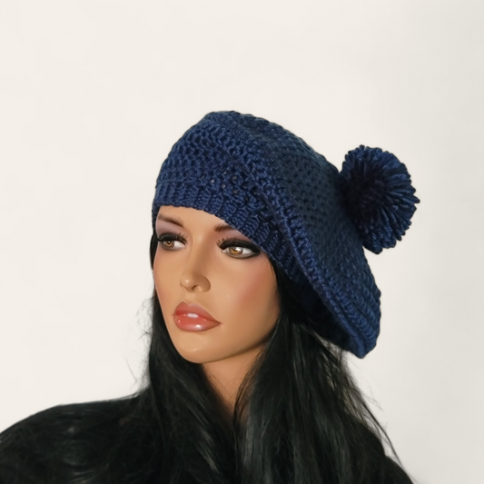 Indigo blue crocheted beret with pom-pom on mannequin.