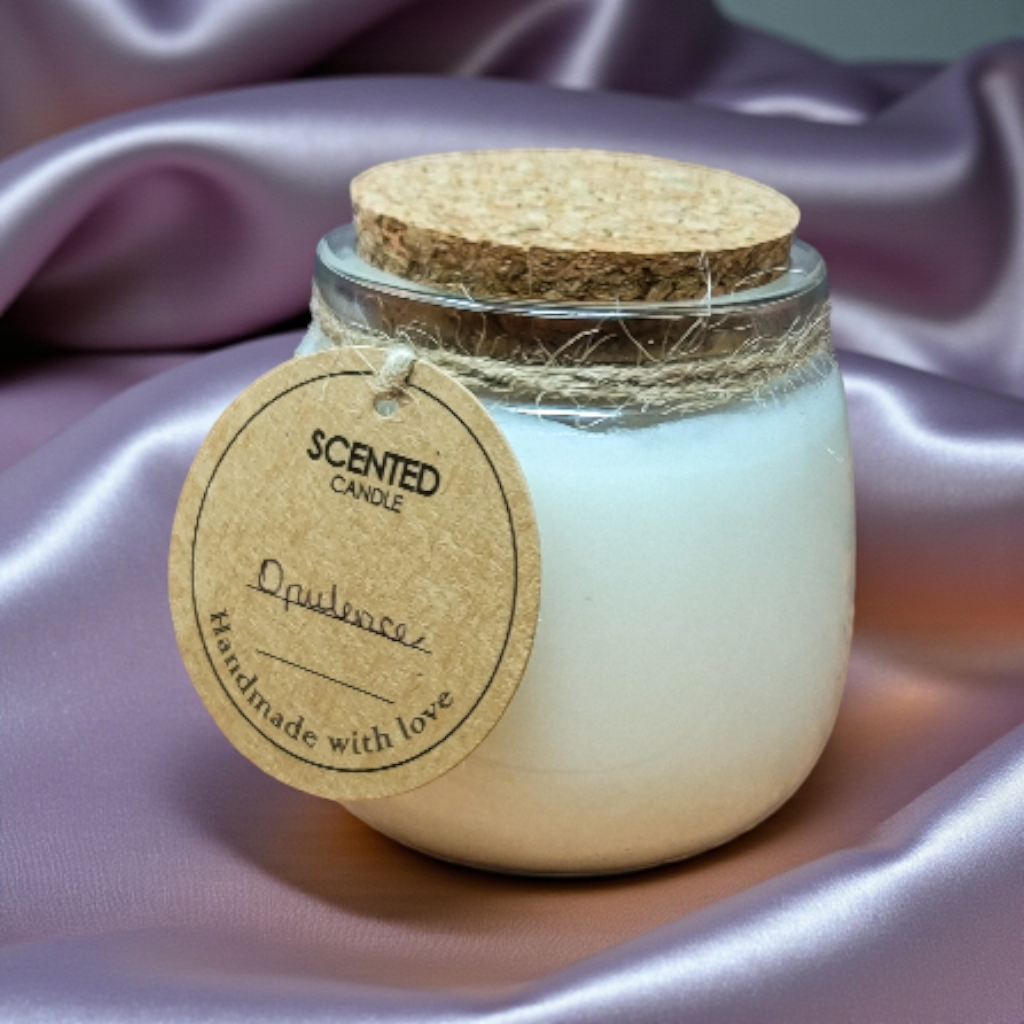 Scented candle in a glass jar with a cork lid on a soft purple fabric background