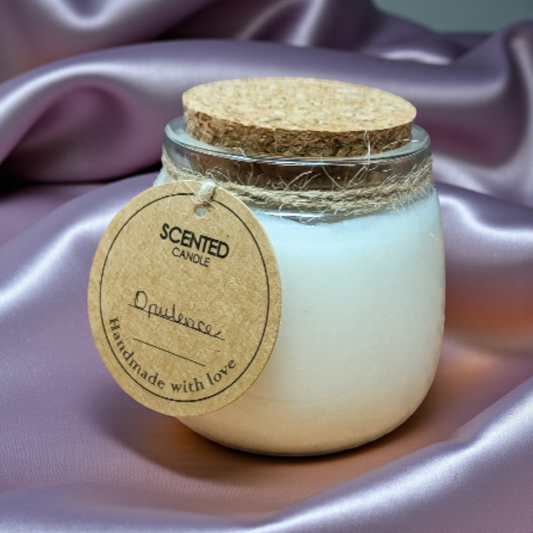 Scented candle in a glass jar with a cork lid on a soft purple fabric background