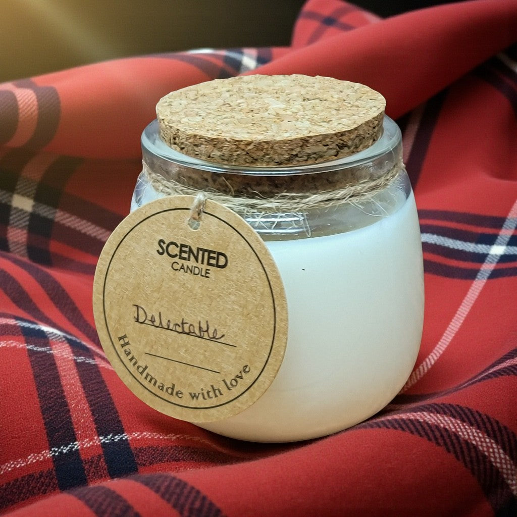 Scented candle in a glass jar with a cork lid on a red plaid fabric background