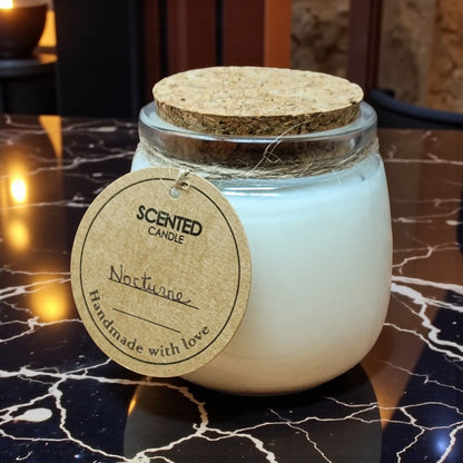 Scented candle in a glass jar with a cork lid on a marble surface