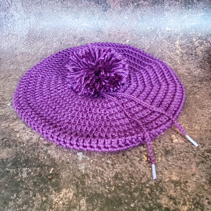 Purple crocheted beret with pom-pom, flat lay.