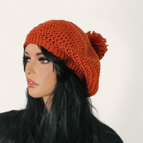 Rusty orange crocheted beret with pom-pom on mannequin