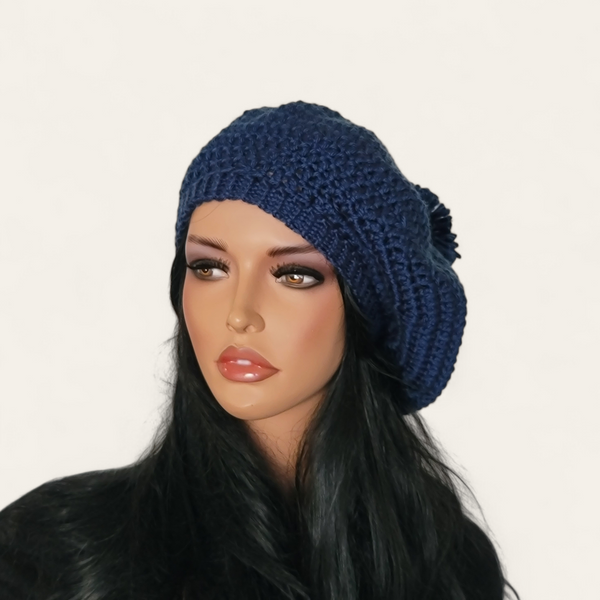 Indigo blue crocheted beret with pom-pom on mannequin.