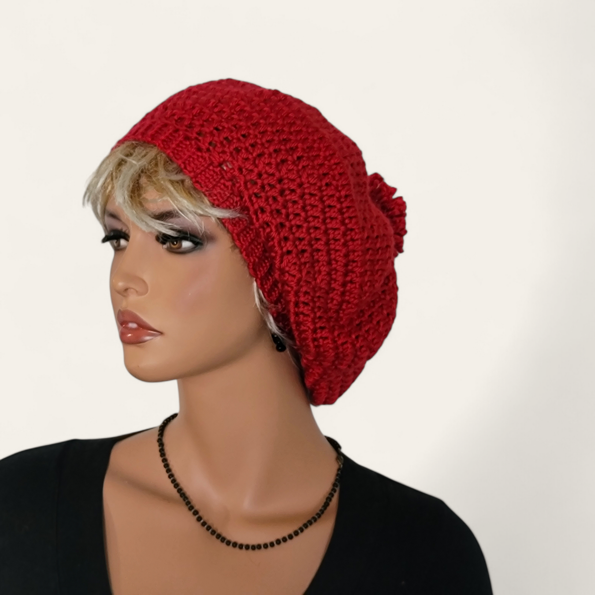 Red crocheted beret with pom-pom on mannequin