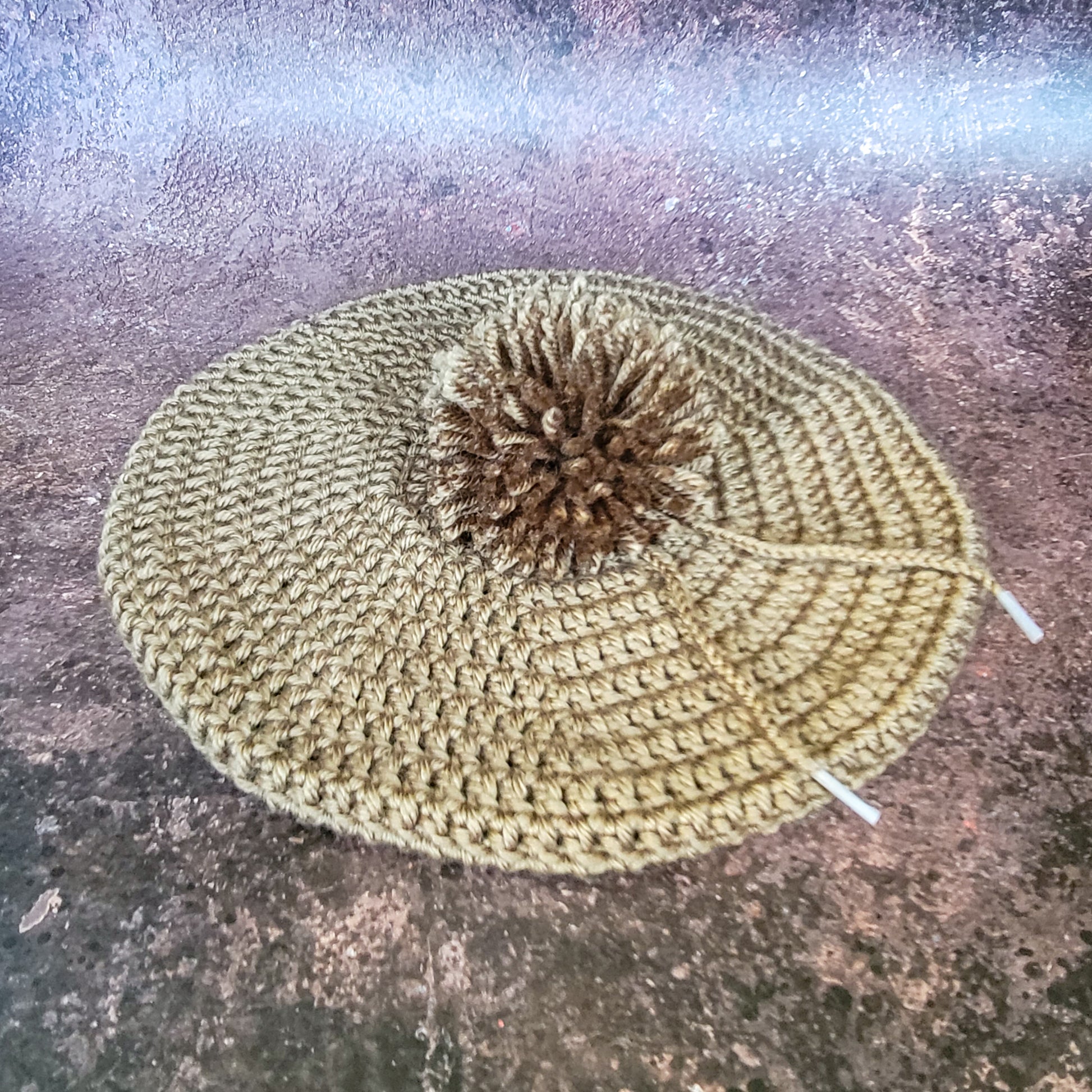 Walnut brown crocheted beret with pom-pom, flat lay.