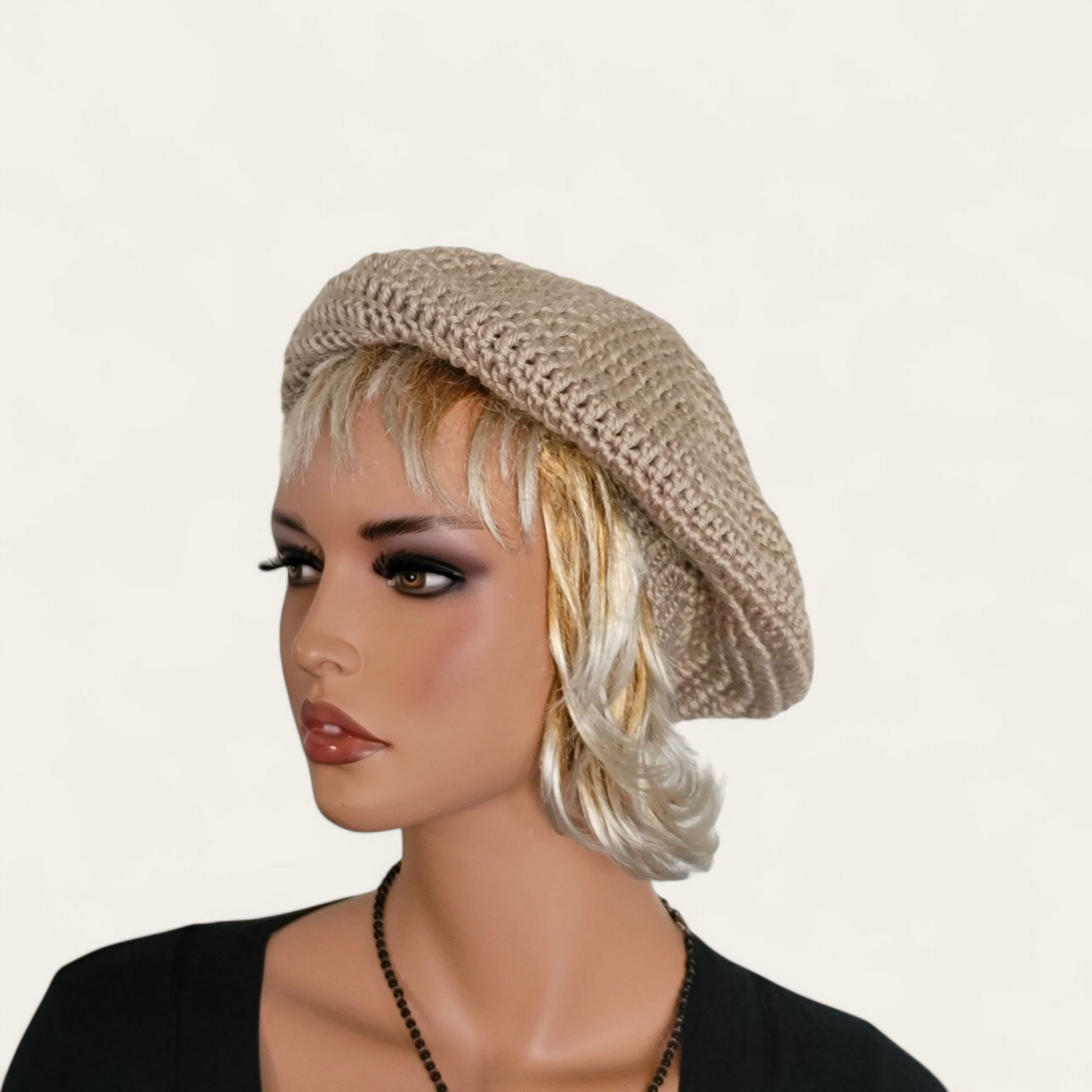 Tan crocheted beret with pom-pom on mannequin.