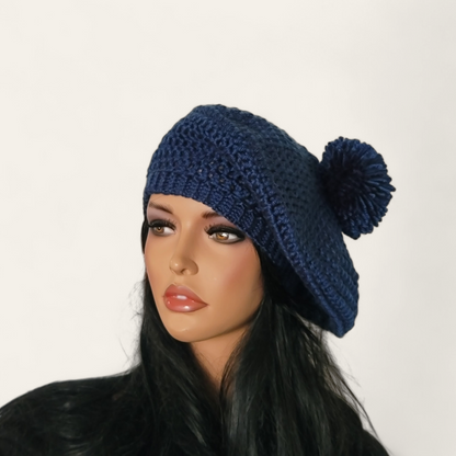 Indigo blue crocheted beret with pom-pom on mannequin. 