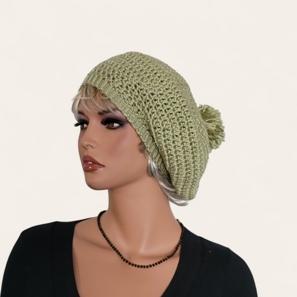 Celery green crocheted beret with pom-pom on mannequin.