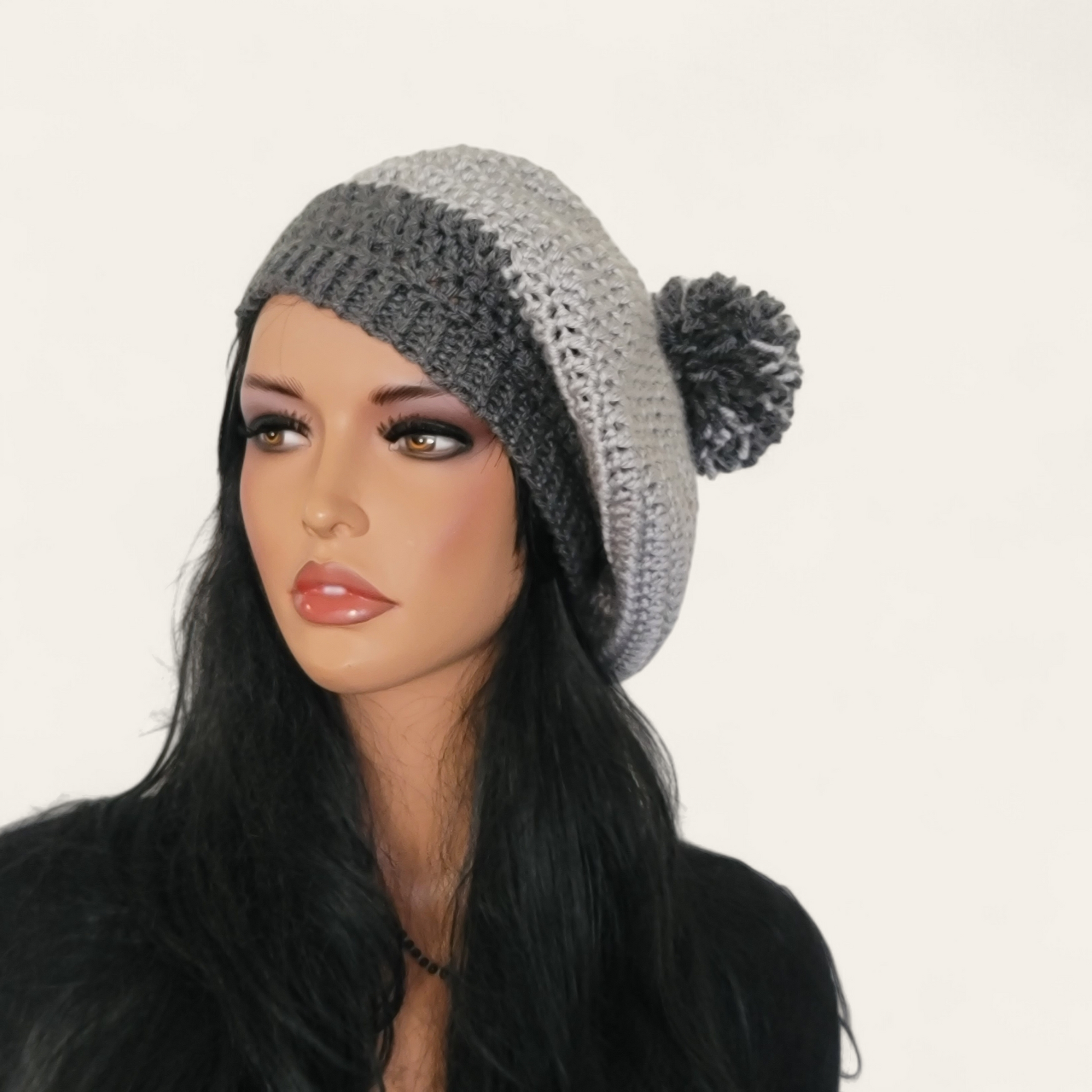 Two-toned grey crocheted beret with pom-pom on mannequin.